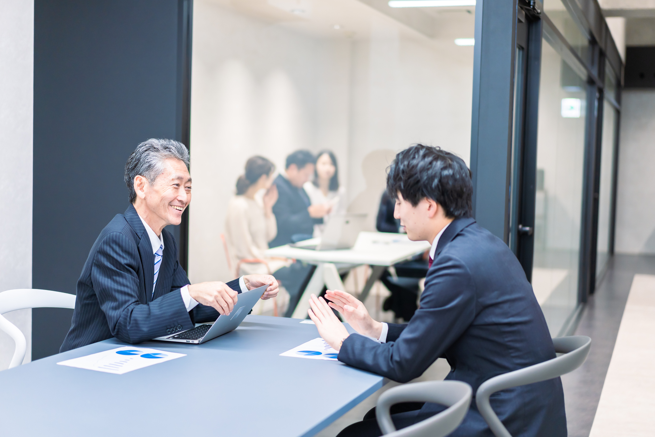 新入社員とOJT担当者が、落ち着いた雰囲気で資料を見ながら進捗や相談事項を確認している場面